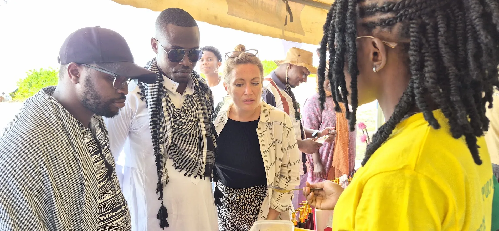 A HERI team member in a yellow T-shirt shows visitors products at an outreach stand