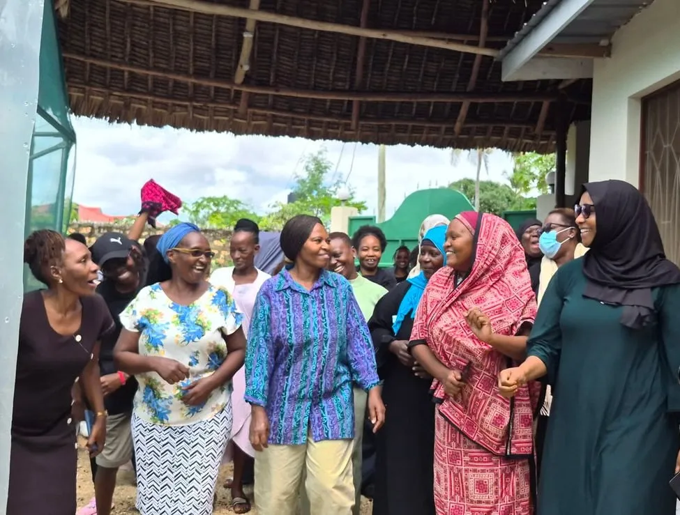 Smiling women from a community group arrive together for a HERI-Kenya meeting in Diani